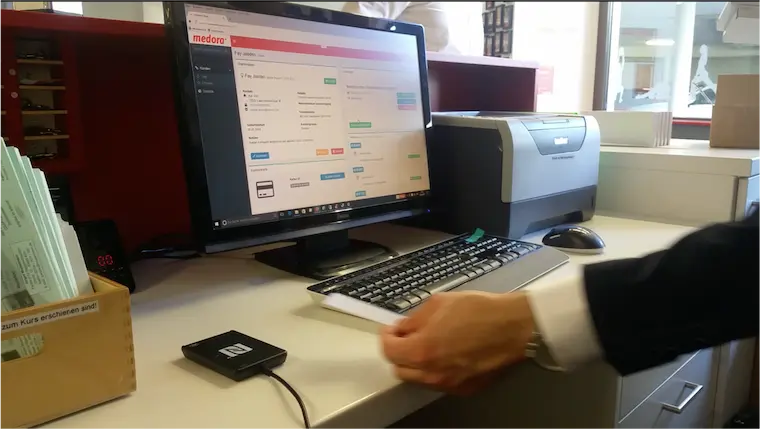 Automatisierte Kundenkarten-Erfassung mit NFC-Technologie – Arbeitsplatz mit PC, Lesegerät und Software zur kontaktlosen Datenübertragung.